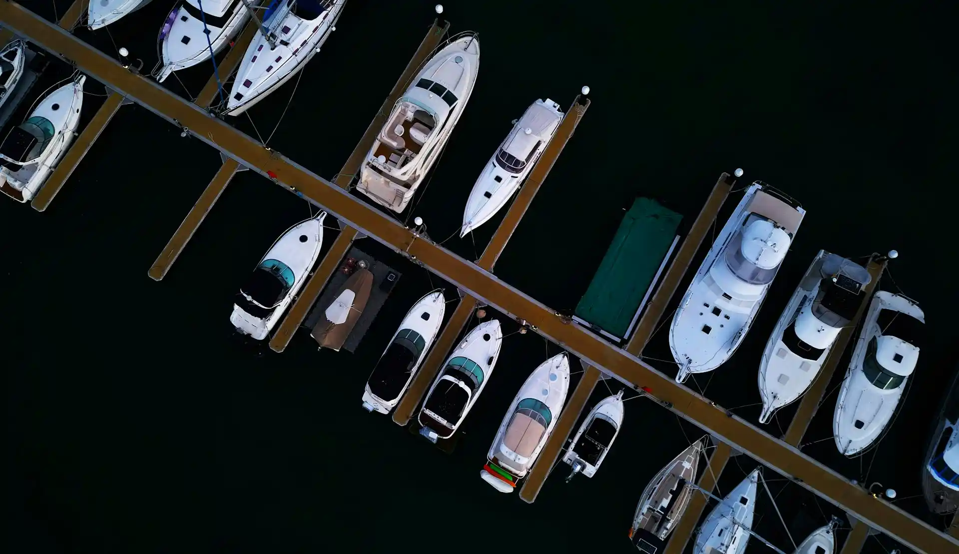 An overhead view of various boats neatly docked in a marina, prompting consideration of What amenities do houseboats offer.